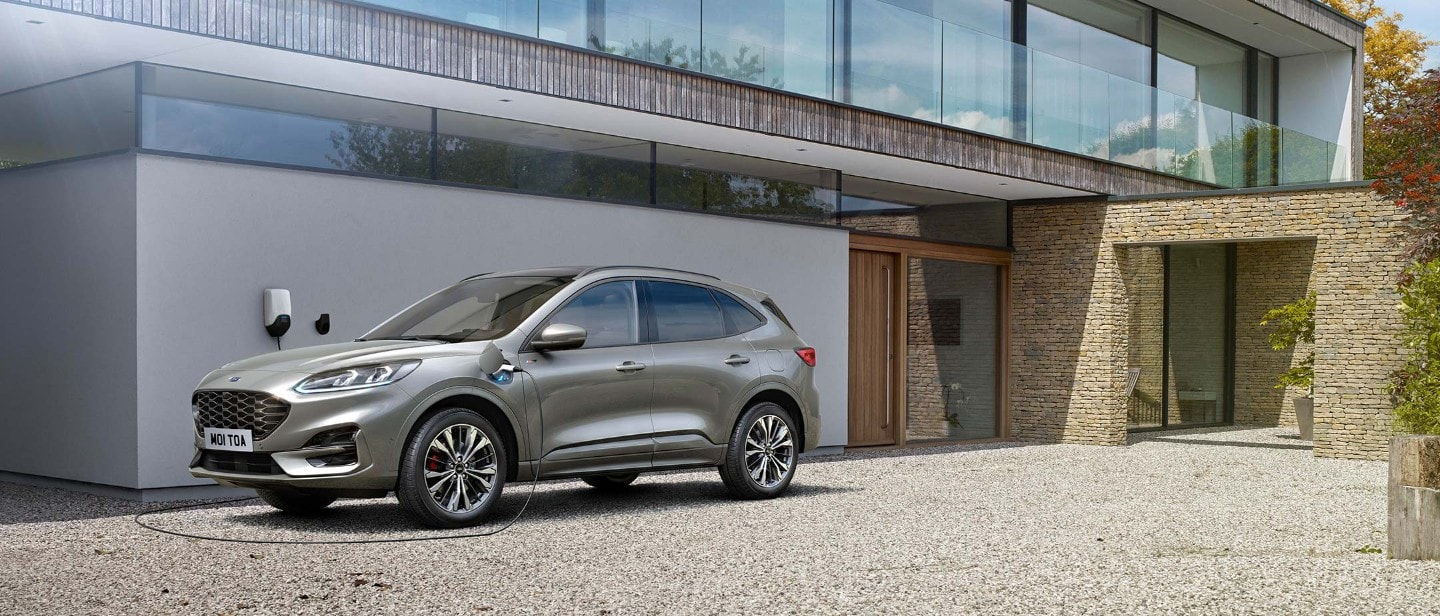 image of a Grey Ford Kuga charging at home via an ev charging cable connected to a wallbox.