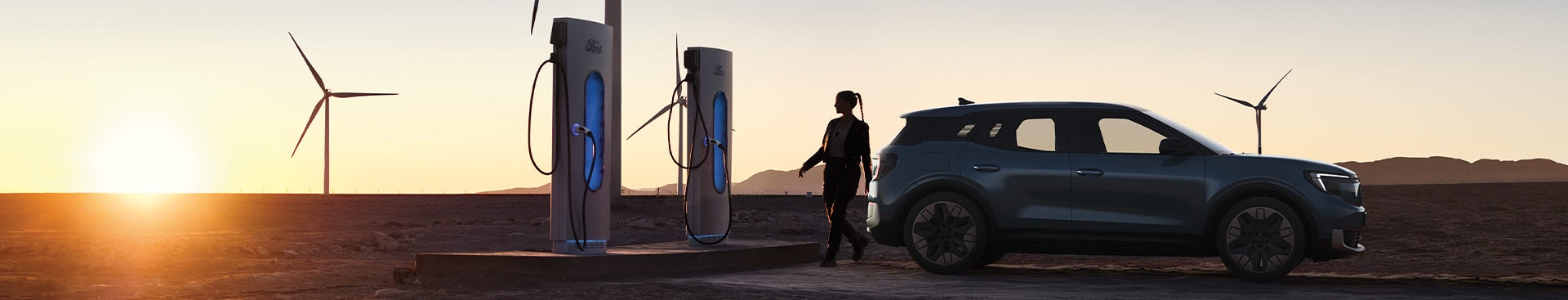 A woman charging a Ford electric car at a public EV charging station.