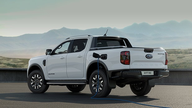 Frozen white Ford Ranger Raptor charging, connected to an electric charging cable