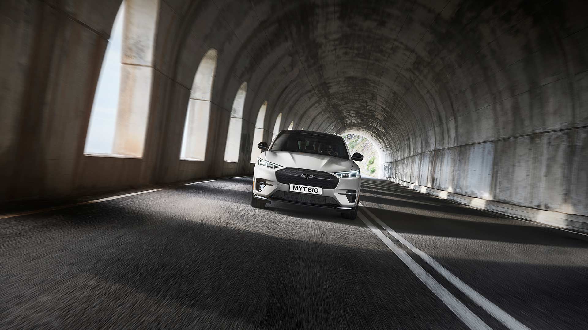 A silver Ford Mustang Mach-E electric car driving through a tunnel. 