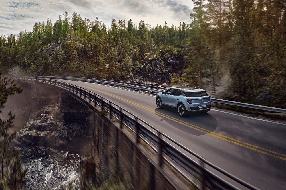 A blue Ford Explorer family SUV driving through mountain scenery.