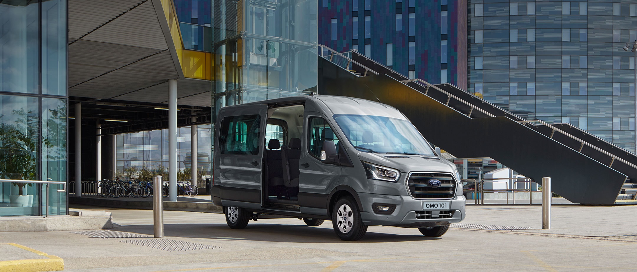 New Ford Transit Minibus parked in front of a modern building with the side door open